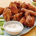 Juicy and crispy chicken wings glazed with spicy sauce and served with a dip.